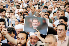 In mourning: A man holds up a picture of former Egyptian president Mohamed Morsi during a symbolic funeral prayer in the courtyard of Fatih Mosque in Istanbul, Turkey, on Tuesday. 

