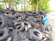 A man piles tires up on the side of a road in Gunung Putri, Bogor, West Java, on Tuesday. The tires were rejected products that the manufacturer had meant to sell to used tire collectors. They were cut in half to prevent them from being misused.