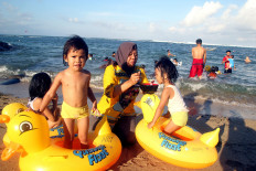 Eat and play: Asni feeds her toddlers while they play on Sindu Beach in Sanur, Denpasar. JP/ Zul Trio Anggono