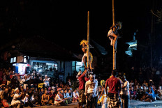 Two dancers climb up bamboo poles during the dance. JP/Agung Parameswara