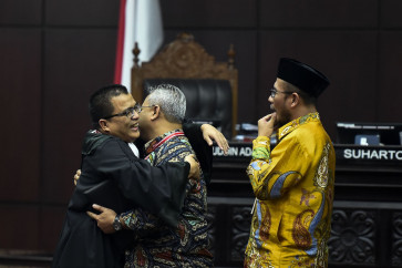 The head of General Elections Commission, Arief Budiman (center), hugs a member of the legal team of the Prabowo Subianto-Sandiaga Uno camp, Denny Indrayana, on June 21.