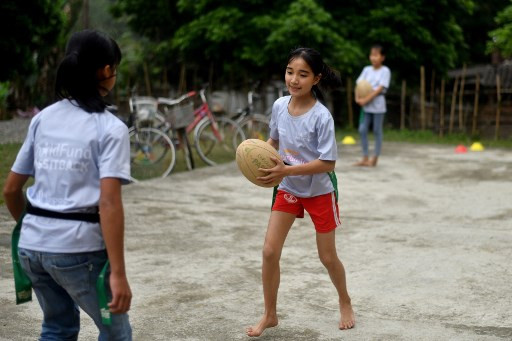 This picture taken on March 17, 2019 shows girls attending a rugby clinic in the Kim Boi district of Vietnam's Hoa Binh Province. Barefoot and muddied, a group of youngsters sprint across a makeshift pitch in rural Vietnam, passing the ball in a game of touch rugby in a country where few people have ever heard of the sport.
