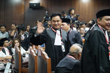Yusril Ihza Mahendra, head of the Joko Widodo-Ma'ruf Amin campaign legal team, waves to photographers prior to an election dispute hearing in June 2019.