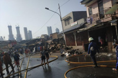 Fire fighters and residents are seen around the site of a fire on Jl. Jati Bundar in Kebon Kacang subdistrict, Tanah Abang, Central Jakarta, on June 30, 2019. A total of 21 of 150 residents in a dense neighborhood in Kebon Kacang subdistrict, Central Jakarta, who underwent rapid testing for COVID-19 on Monday have tested positive for the SARS-CoV-2 virus.