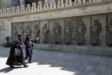 Women walk past bas reliefs showing ancient Persian soldiers at a park in the centre of the Iranian capital Tehran on May 28, 2019. 
 