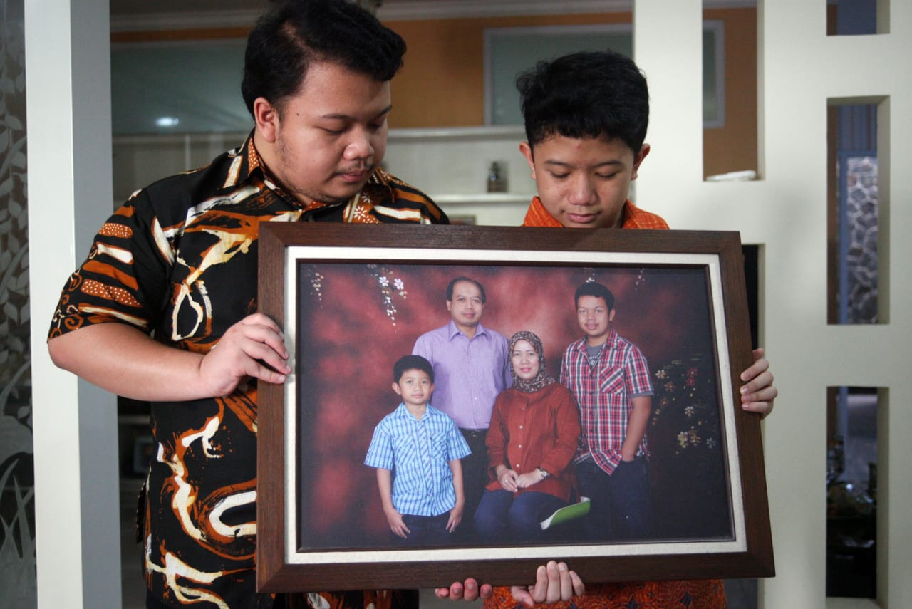 Muhammad Ivanka Rizaldi Nugroho (left) and Muhammad Aufa Wikantyasa Nugroho (right), sons of the late Sutopo Purwo Nugroho, National Disaster Mitigation Agency (BNPB) spokesman, hold up a family picture at their residence in Depok, West Java, on Sunday. Sutopo died in Guangzhou, China, at 2 a.m. local time, after more than a year battling lung cancer.