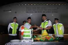 Garuda Indonesia president director Ari Askhara (second right) gives a plate of yellow rice to an official in charge of this year's first departure of haj pilgrims at Adi Soemarmo Airport in Boyolali, Central Java, on Sunday. The background shows the airplane with the controversial sticker.