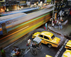 At pause: A man is seen on the streets of Kolkata, India pulling a rickshaw against the background of a speeding train. 