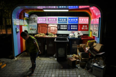 In this photo taken on July 11, 2019, a woman walks past a waste collection point at a residential area in Shanghai. 