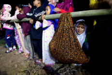 Balancing act: A mother attends JiFolk preevent show while rocking her baby to sleep on a swaddle carrier hung on a bamboo pole. JP/PJ Leo