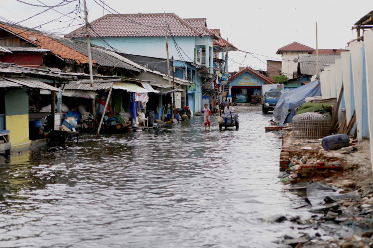 Residents walk past tidal flood in Muara Angke, North Jakarta in 2017. 