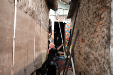 Khomariah, 49,  checks the pipe she uses to collect rainwater next to her house in a fishing village in Kamal Muara, Penjaringan, North Jakarta, on July 13.