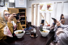 Two Indonesian Muslim tourists are taking picture of their halal ramen. JP/Rosa Panggabean