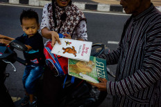 Rini and her son, Devan, return a picture book they borrowed from Sutopo's Becak Pustaka. JP/Anggertimur Lanang Tinarbuko