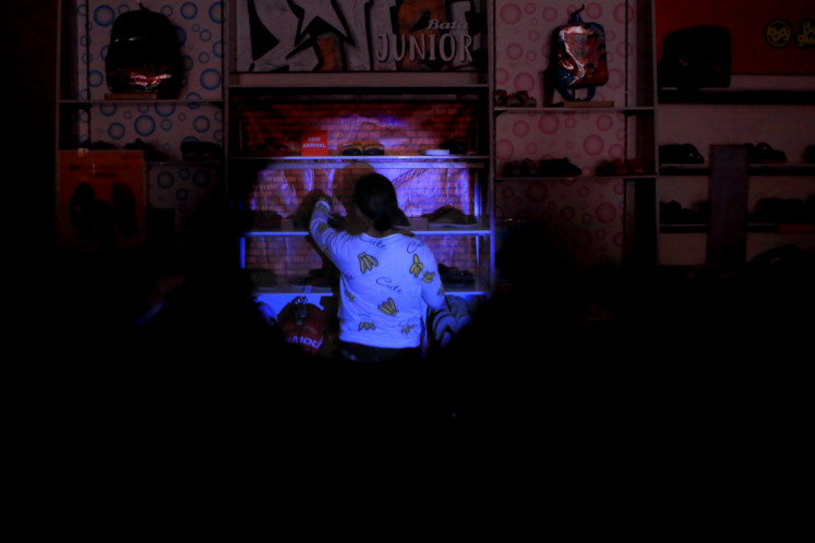 A customer observes displayed shoes during blackout in Jakarta on Aug. 5, 2019. 
