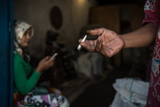 A tobacco seller in Parakan smokes a kretek cigarette in his warehouse. JP/Dottie Bond
