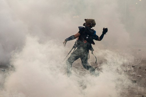 This file photo taken on August 5, 2019 shows a protester throwing a brick back at the police after they fired tear gas in Wong Tai Sin during a general strike in Hong Kong, as simultaneous rallies were held across seven districts. Hong Kong protesters who have taken to the streets for nearly two months are harnessing everything from traffic cones to kitchenware to battle tear gas as demonstrations escalate.