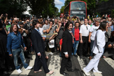 Beatles lookalike band 'Fab Gear' and fans of The Beatles pose at the famous Abbey Road zebra crossing in London, England on August 8, 2019, the 50th anniversary of the day that the iconic Beatles album cover photograph was taken. 