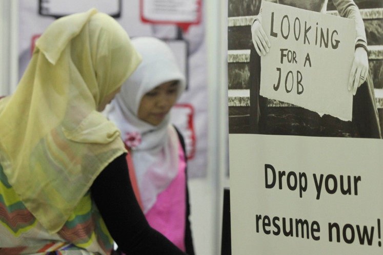 Pursuing opportunity: Two jobseekers study job openings during an employment fair on Aug. 23, 2013, at the Mega Career Expo in Balai Kartini, Jakarta.
