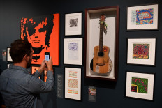 A visitor takes a photograph of British musician Ed Sheeran's 'Martin' guitar, used by the artist between 2008-2012, during a press preview of the exhibition 'Ed Sheeran: Made in Suffolk' in Ipswich, east England on August 19, 2019. 