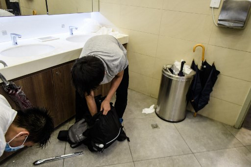 In this picture taken on August 25, 2019, Nick (center), 20, and other protesters get changed into their normal clothes in a public toilet after they attended a protest in Tsuen Wan, an area in the New Territories in Hong Kong. 