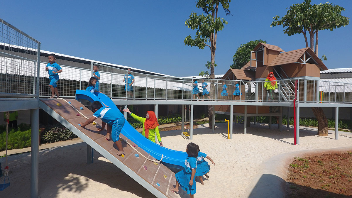 Children cheerfully climb and down a board as they play and explore a kids' area at PAUD Terpadu Kalirejo. The fun activities help develop and improve the children&rsquo;s gross motor skills. 