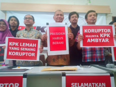 Researchers from various antigraft research centers and Corruption Eradication Committee (KPK) chairman Agus Rahardjo (center) hold up signs urging President Joko "Jokowi" Widodo to stop the House of Representatives from revising the KPK Law.