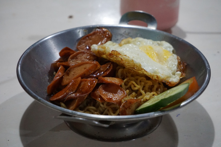 Yummy: A bowl of instant noodles with fried egg, sweet soy sauce-glazed sausages and peppery seasoning served at Warung Mee.