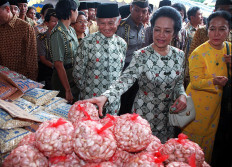 Hasri Ainun Habibie and her husband, Indonesian President B.J.Habibie (C), examine garlic at a cheap market set up in the National Monument Park in Jakarta, 09 January. Food and other basic needs are being offered at discount prices during the three-day event, which was opened by Hasri on Saturday. AFP/Kompas 