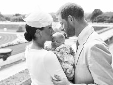 This official handout Christening photograph released by the Duke and Duchess of Sussex shows Britain's Prince Harry, Duke of Sussex (R), and his wife Meghan, Duchess of Sussex holding their baby son, Archie Harrison Mountbatten-Windsor at Windsor Castle with the Rose Garden in the background, west of London on July 6, 2019.
