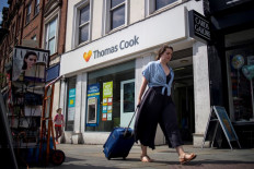 Pedestrians are pictured walking past a branch of a Thomas Cook travel agent's shop in London.  (AFP/Tolga Akmen).
Usage: 0