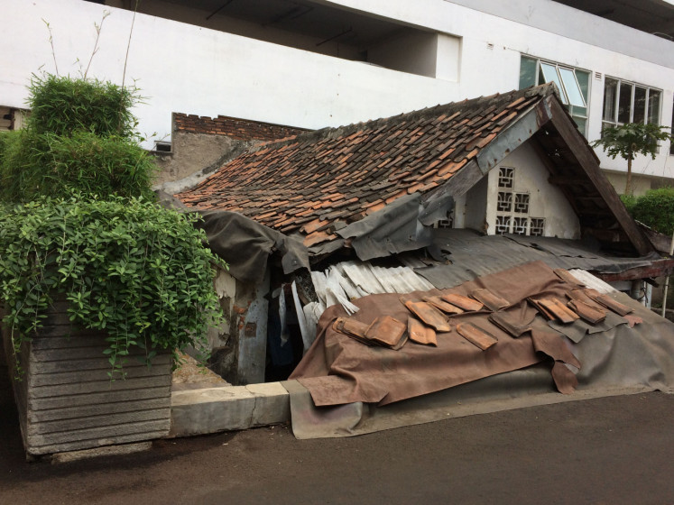 Staunch defiance: An old house owned by Elis, 60, peaks out from below an access road to the Thamrin Executive Residence apartment complex in Central Jakarta on Saturday. The owner has refused to sell her house, despite being offered a substantial pay-out.