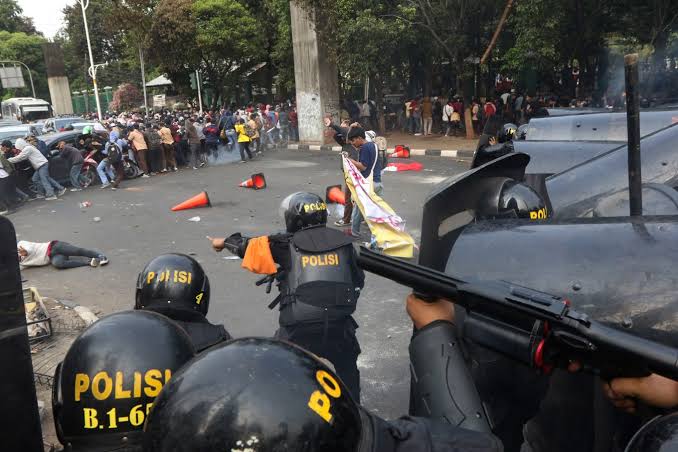 Line of fire: A police officer aims a riot gun at protesters, mostly high school students, near the House of Representatives building in Senayan, Central Jakarta, on Wednesday.