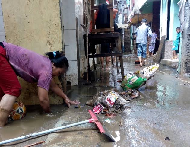 People living on Jl. Kebon Pala II in Makassar, East Jakarta, clean mud and trash brought by floodwater on Oct. 9. 