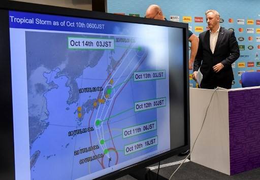 Tournament director of the Japan 2019 Rugby World Cup Alan Gilpin (right) walks past a screen showing the path of the approaching typhoon Hagibis, which will affect upcoming World Cup matches, in Tokyo on October 10, 2019. Rugby World Cup organisers took the unprecedented step of cancelling games -- England v France, and New Zealand v Italy -- on October 10 as Super Typhoon Hagibis bears down on Japan.

