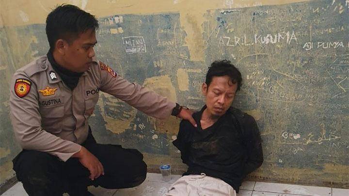 A police officer holds a man identified as Abu Rara, the suspect in the stabbing of Coordinating Political, Legal and Security Affairs Minister Wiranto in Pandeglang, Banten on Oct. 10. 