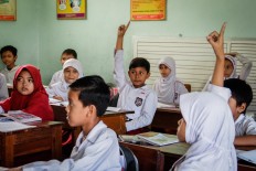 Rizki raises his hand to answer the teacher's question.JP/ Anggertimur Lanang Tinarbuko