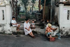 Rizki, his grandmother and brother sit together near a street vendor. JP/ Anggertimur Lanang Tinarbuko