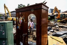 A child is seen in a mirror witnessing houses being torn down in Sunter, North Jakarta, on Nov. 18. The North Jakarta administration cleared the area to make way for a river restoration project.