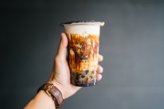 Close up of a hand holding the famous black sugar bubble tea from Tiger Sugar