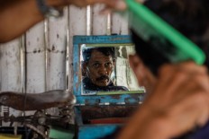 A man observes his haircut from a mirror. JP/Anggertimur Lanang Tinarbuko