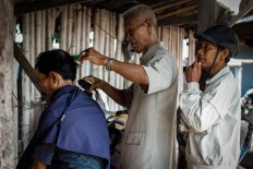 One of Suhardi’s customers waits in line to get a haircut. JP/Anggertimur Lanang Tinarbuko