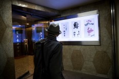 A man walks past the board of Sukiyabashi Jiro sushi restaurant (2nd R) in Tokyo on November 26, 2019. 