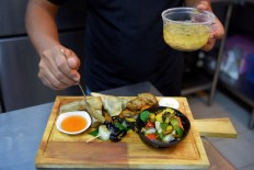 This photo taken on Oct. 24, 2019 shows Chef Seiha Soeun preparing a mixed insect dish with scorpion and spider at the Bugs Cafe restaurant in Siem Reap province. Ant spring rolls, silkworm taro croquettes and a 'bug mac' -- Cambodia's first insect tapas restaurant is mixing cocktail culture with creepy crawler fare.