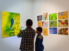 Visitors admire photographs showcased at Wahyu Sigit's exhibition on dragonflies.
