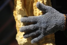 A close-up of a sulfur chunk and a miner's glove. JP/Boy T Harjanto