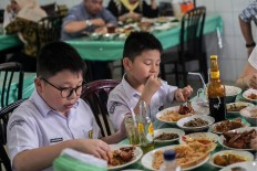 Two children in school uniform enjoy food at a Padang restaurant in Medan, North Sumatra. JP/Andri Ginting