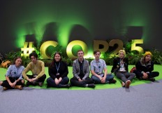 (From left) Argentina's Nicole Becker, Russia's Arshak Makichyian, Australia's Chloe McCann and Toby Thorpe, Netherlands' Erik Christiansson, Sweeden's Vega Minsson and France's Lea Ilardo pose in front of the logo of the UN Climate Change Conference COP25 decorated with plants at the 'IFEMA - Feria de Madrid' exhibition center, in Madrid on December 5, 2019.