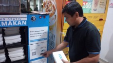 UP FOR GRABS: A man grabs a box of food stored in a FoodBox in Evasari Hospital, Cempaka Putih, Central Jakarta on Dec. 5. He also inserted money into a deposit slot in the FoodBox. The FoodBox stores 100 food boxes daily, which can be taken by anyone for free.