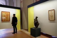 A visitor looks at an artwork during an exhibition of delicate works on paper at the Vatican on December 11, 2019. 